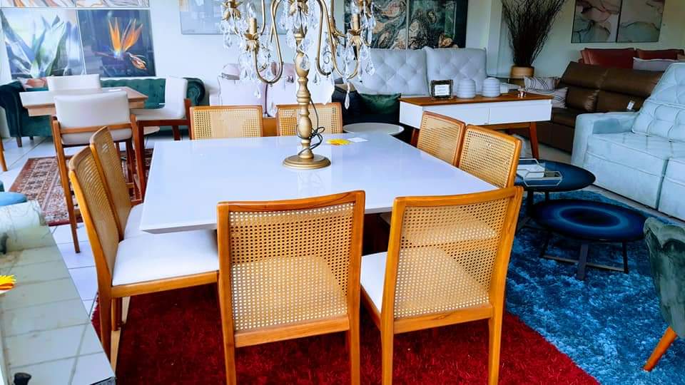 Mesa branca com cadeiras de palhinha e lustre de cristal